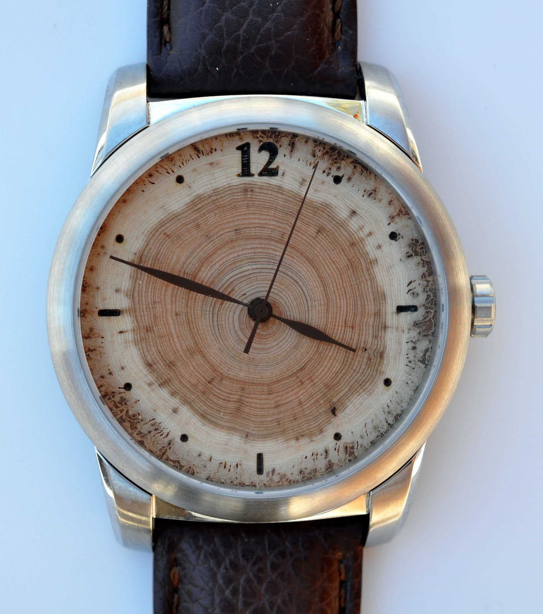 Handcrafted Douglas-fir wood watch dial with unique tree rings, set in a sleek stainless steel casing.