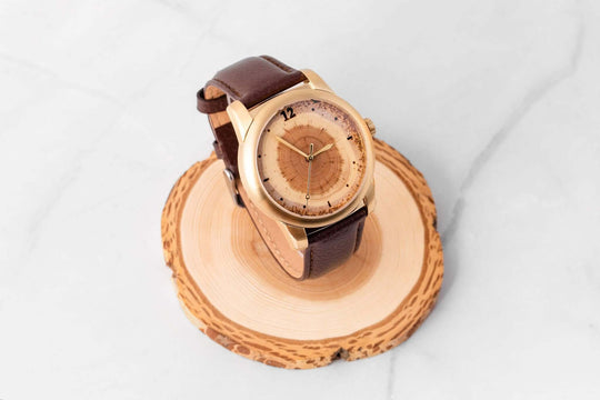 Custom year tree ring watch on a wooden base, showcasing its unique natural design and leather strap.