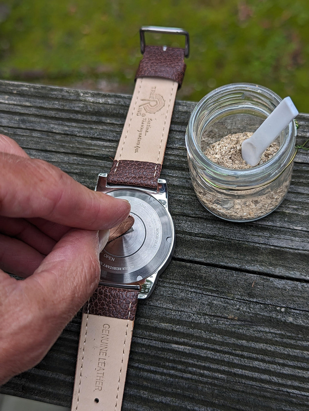 Person opening the compartment of a Tree Ring Memorial Pet Watch to add pet cremation ashes.